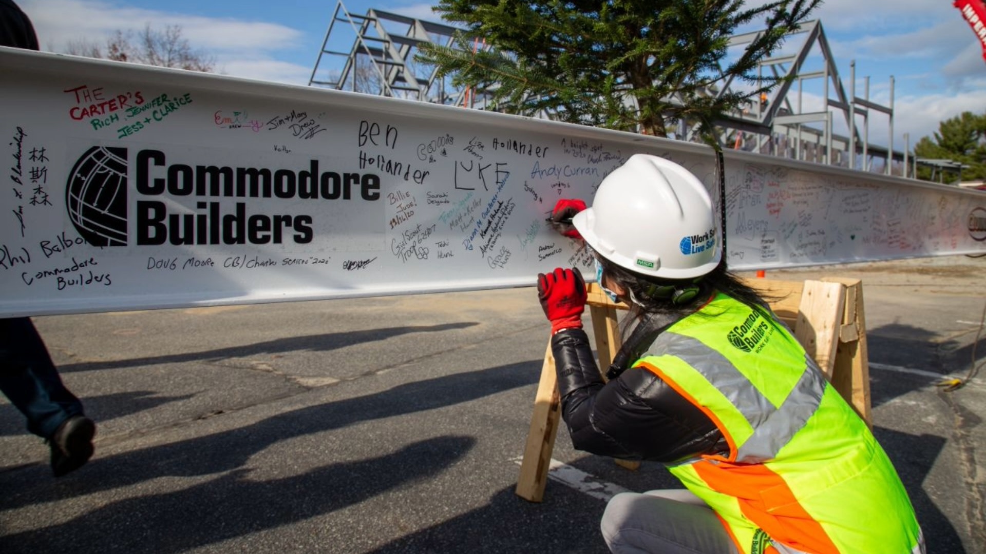 A construction worker looking at the Commodore Builders logo on a wall