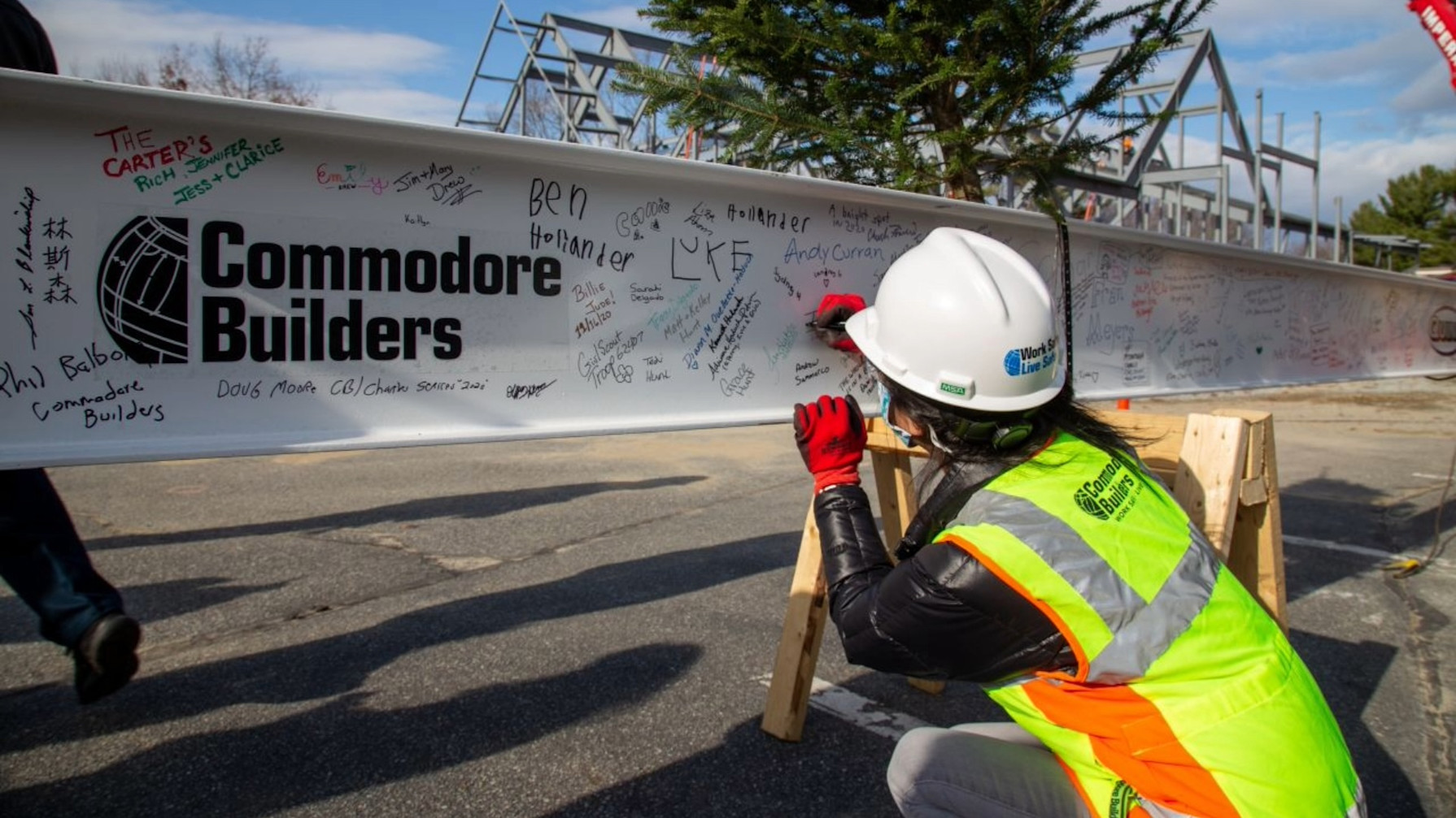 A construction worker looking at the Commodore Builders logo on a wall