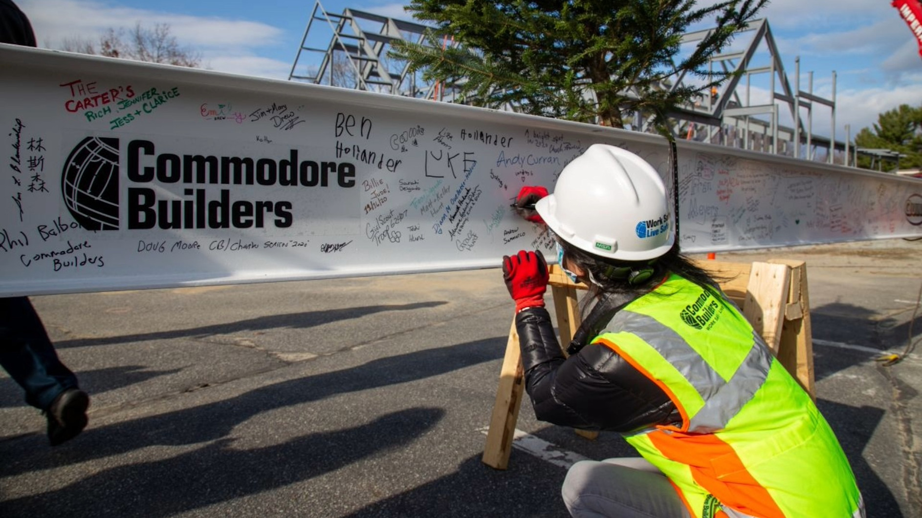 A construction worker looking at the Commodore Builders logo on a wall