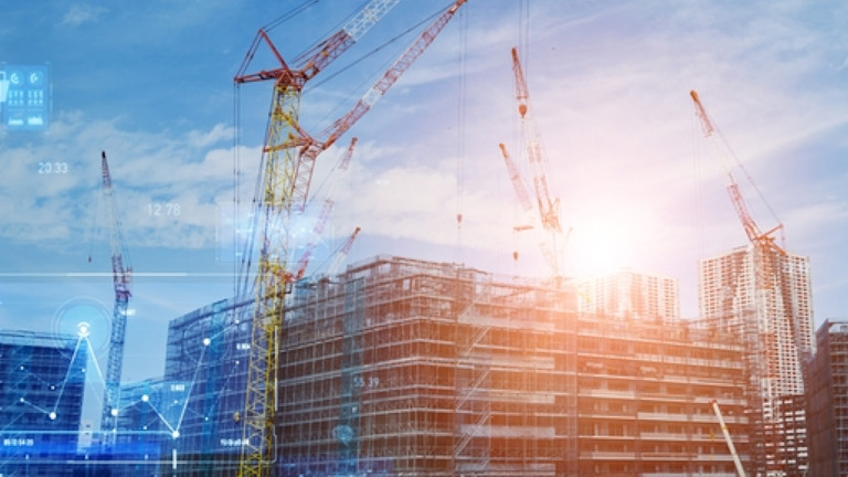 Construction site with cranes and buildings under a clear blue sky