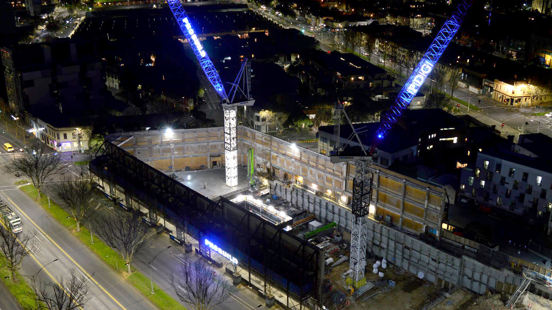 Two PDG cranes lite with blue lights opposing one another at night