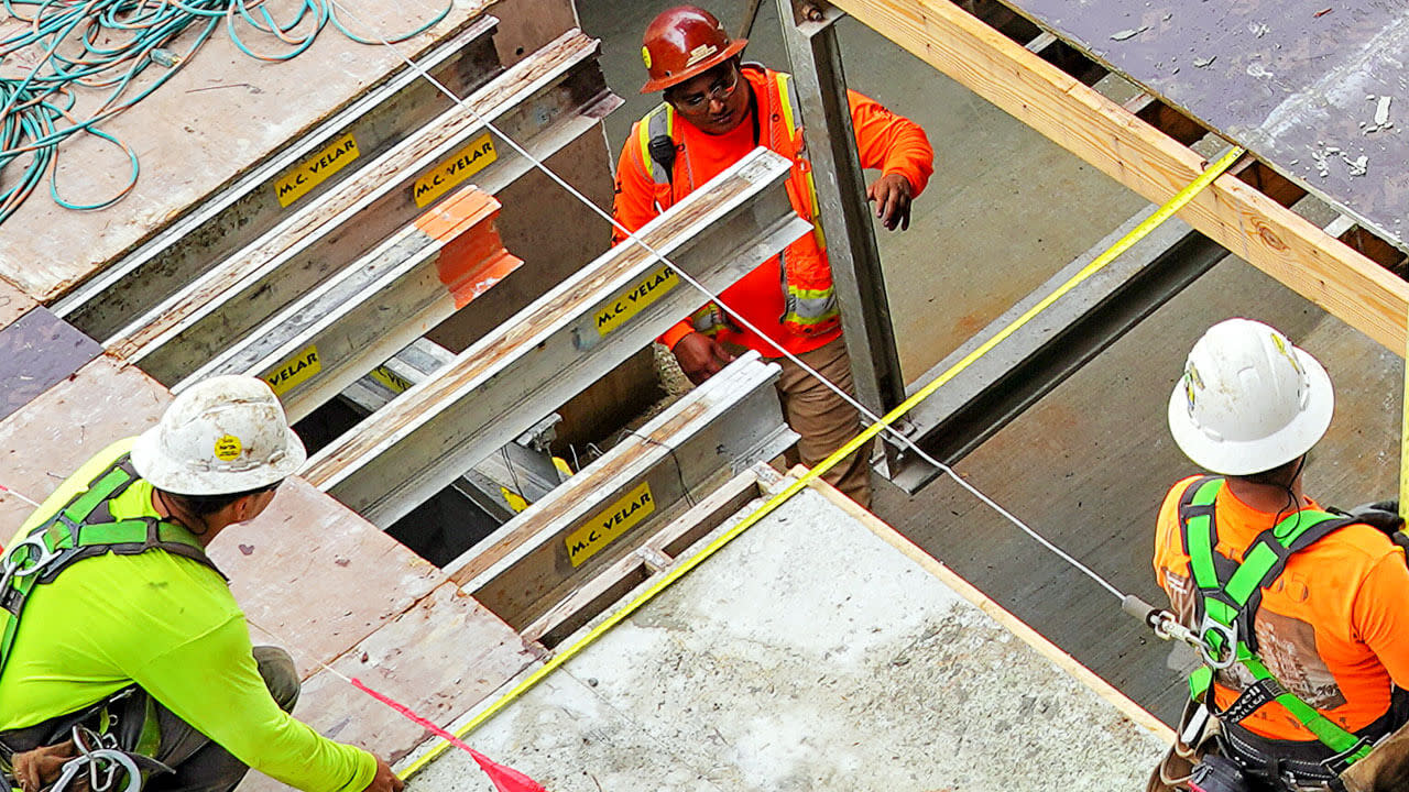 Three construction workers measuring the site