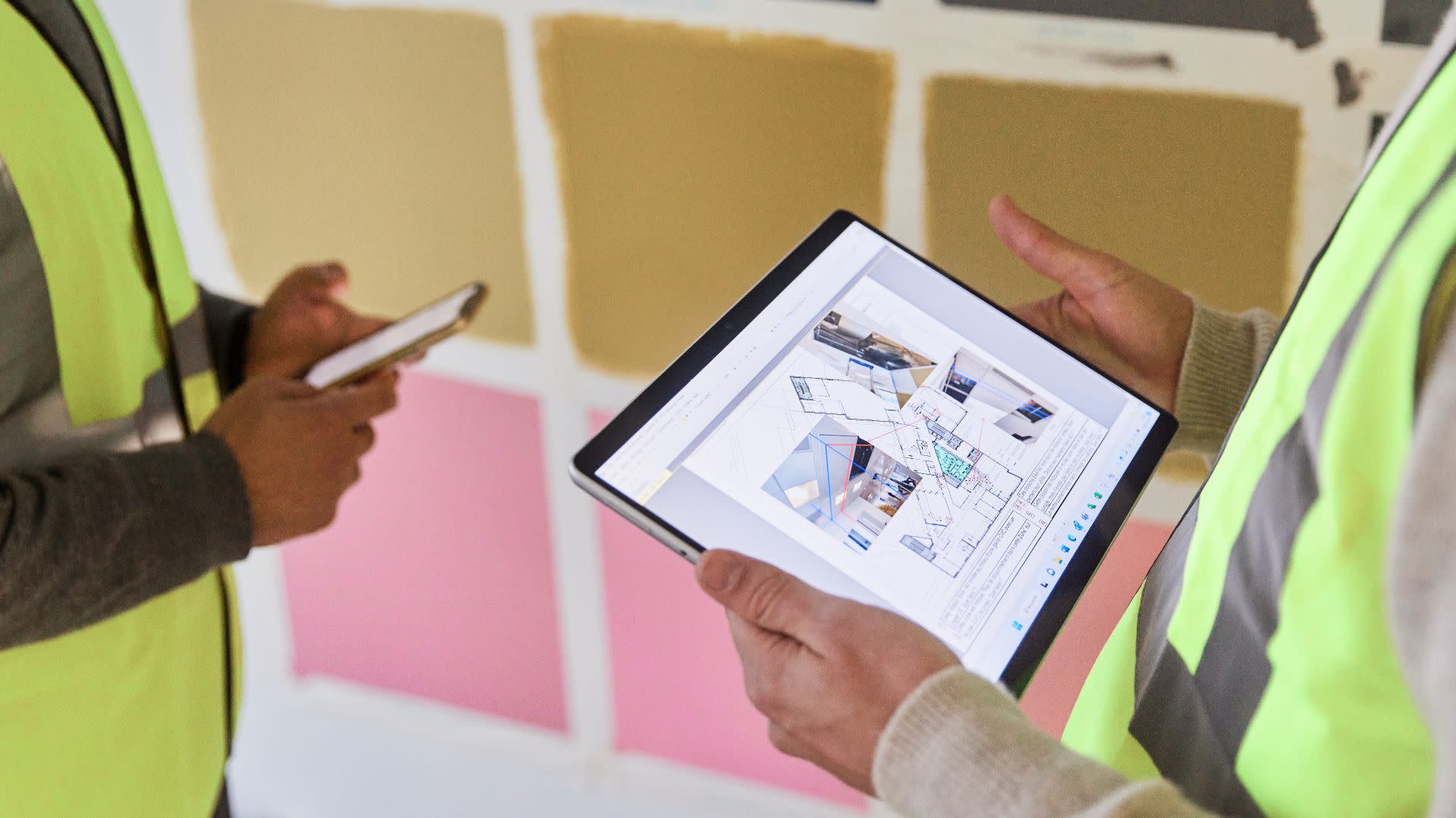 A contractor holding a tablet and another contractor holding a phone