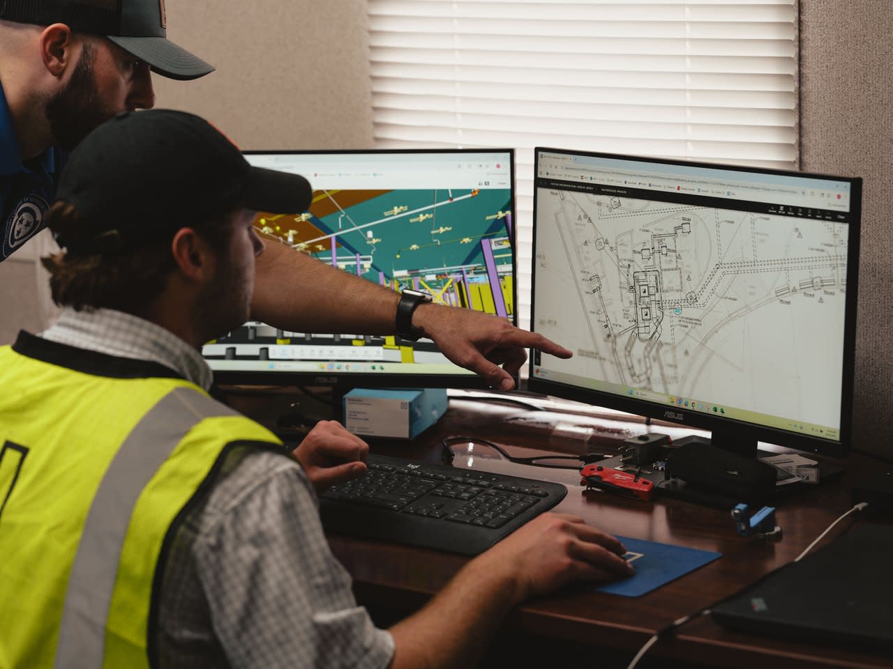 Two contractors looking at blueprints on a desktop
