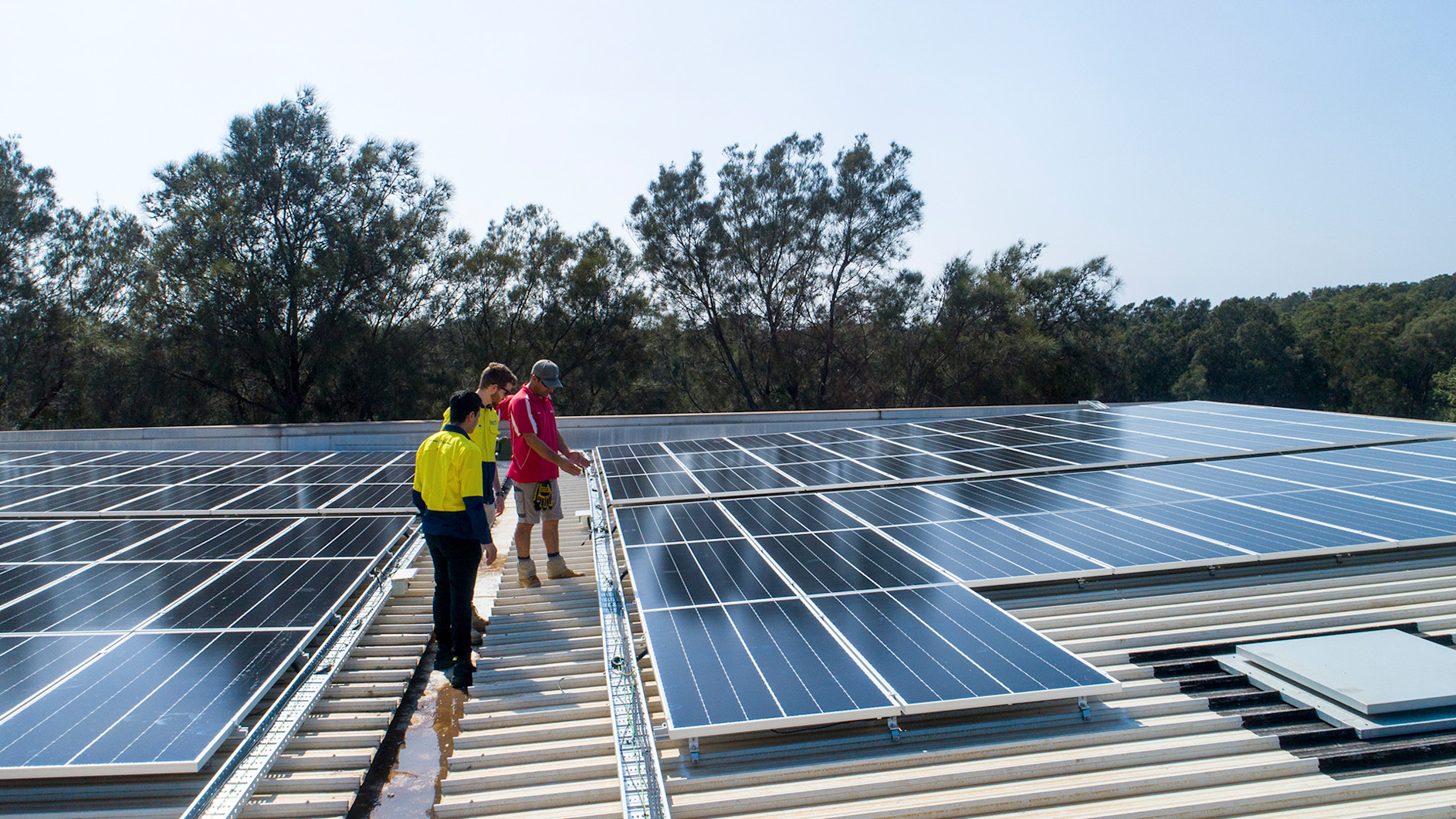 Image of construction workers on a roof inspecting solar panels