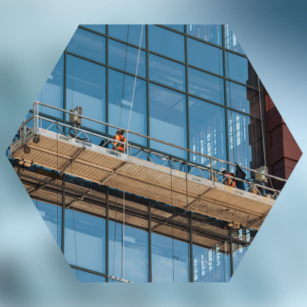 Two construction workers on suspended scaffold cleaning glass facade