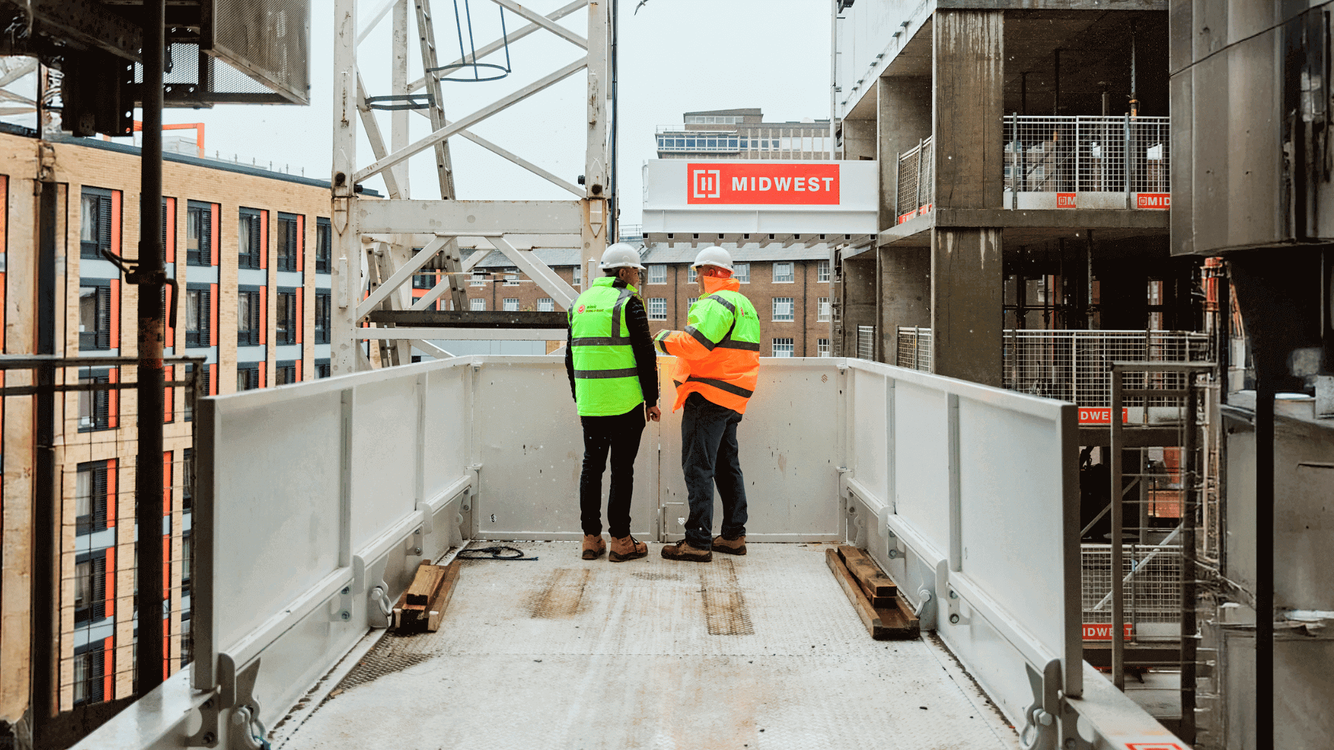 Two construction workers on site and in discussion with each other