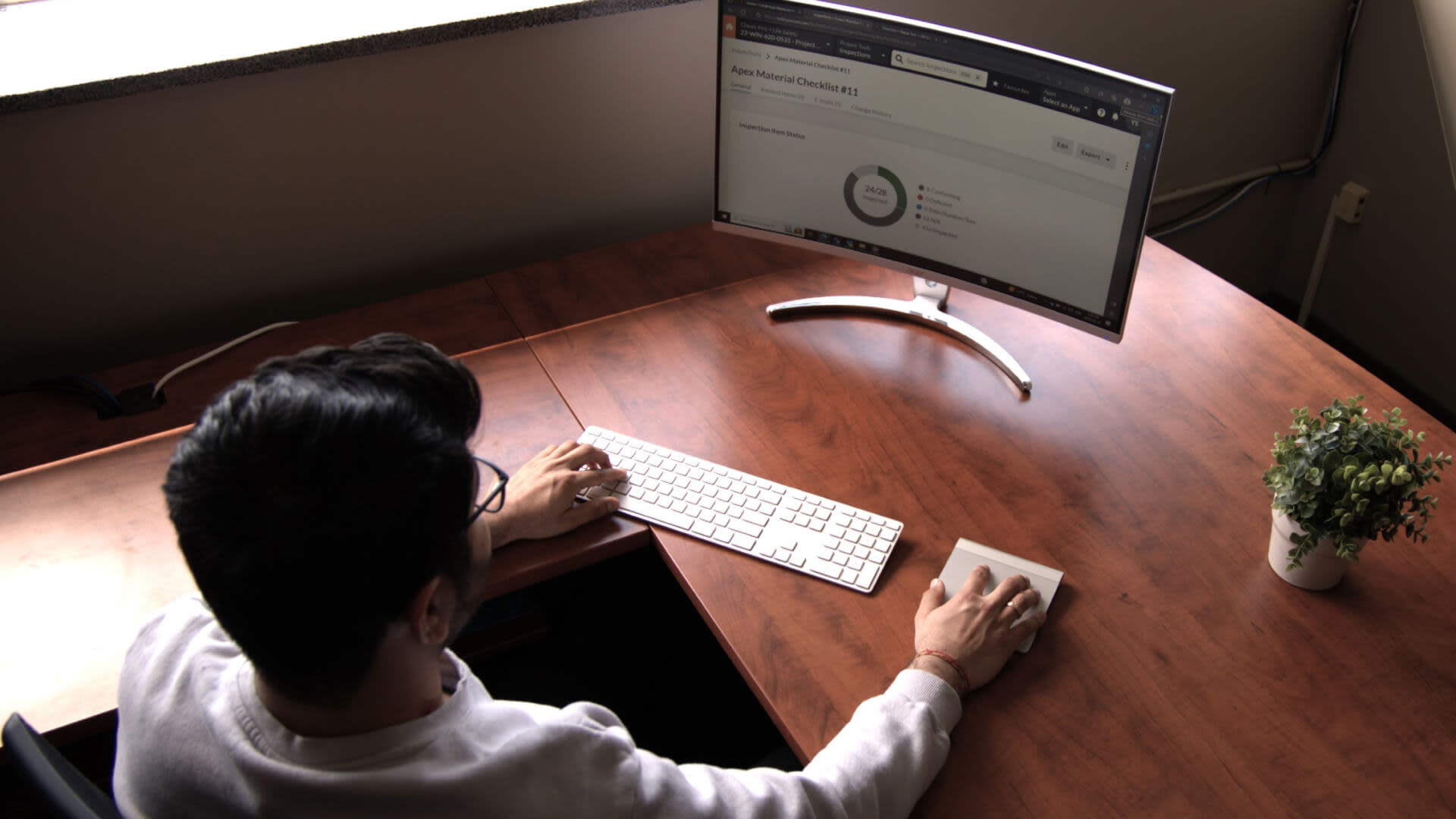 A man working at a desk, using a computer and keyboard