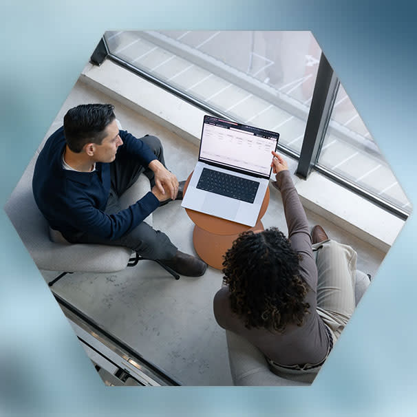 Top down view of two workers discussing Procore on laptop