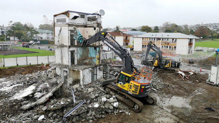 Large machinery tearing down an older building