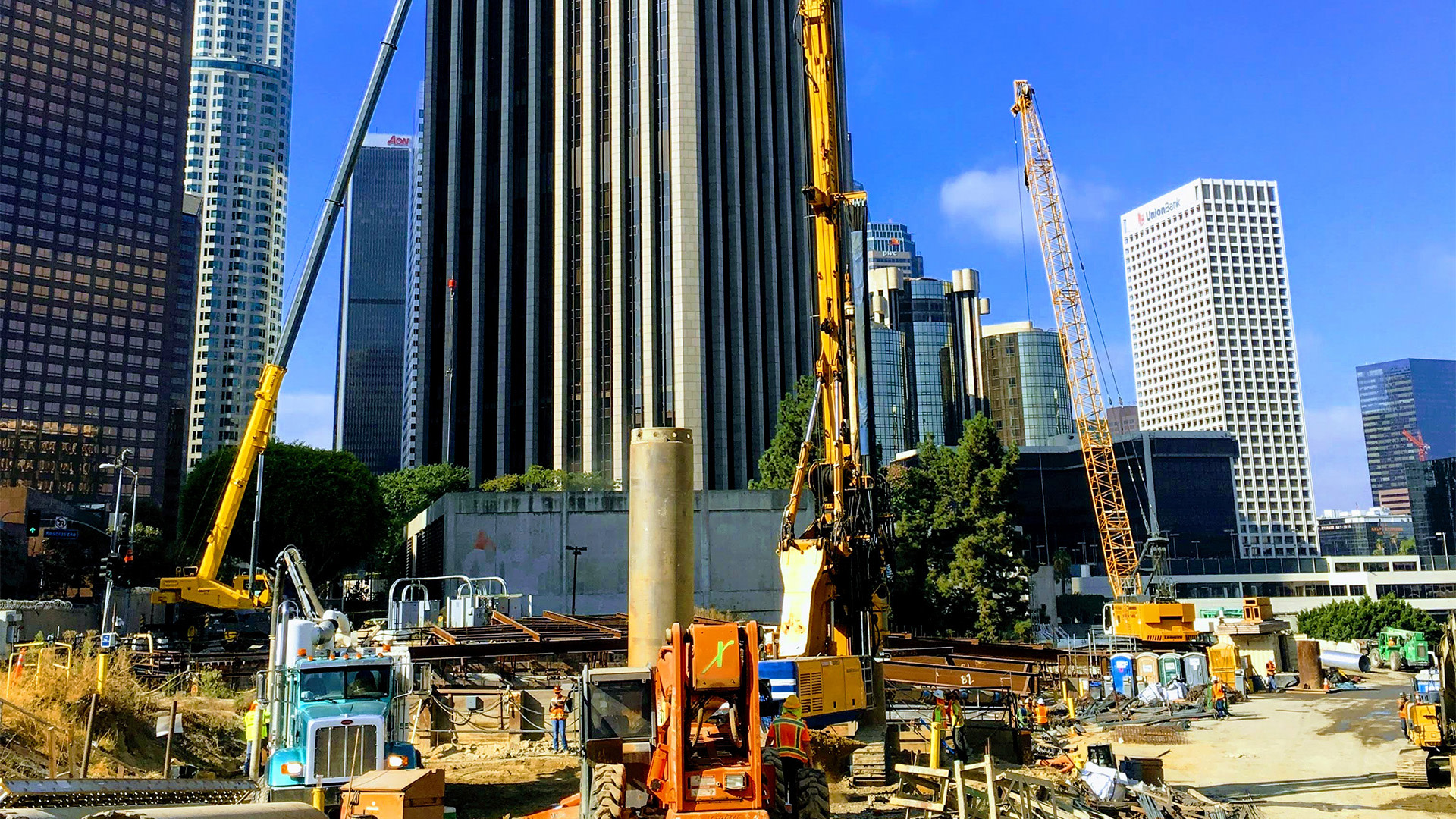 a construction site with cranes and a tall building in the background