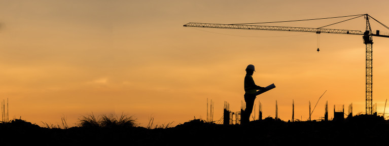 a person holding a hardhat in front of a large oil pump