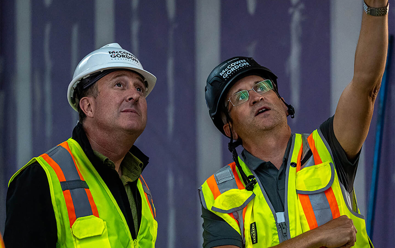 Two contractors pointing up at a construction