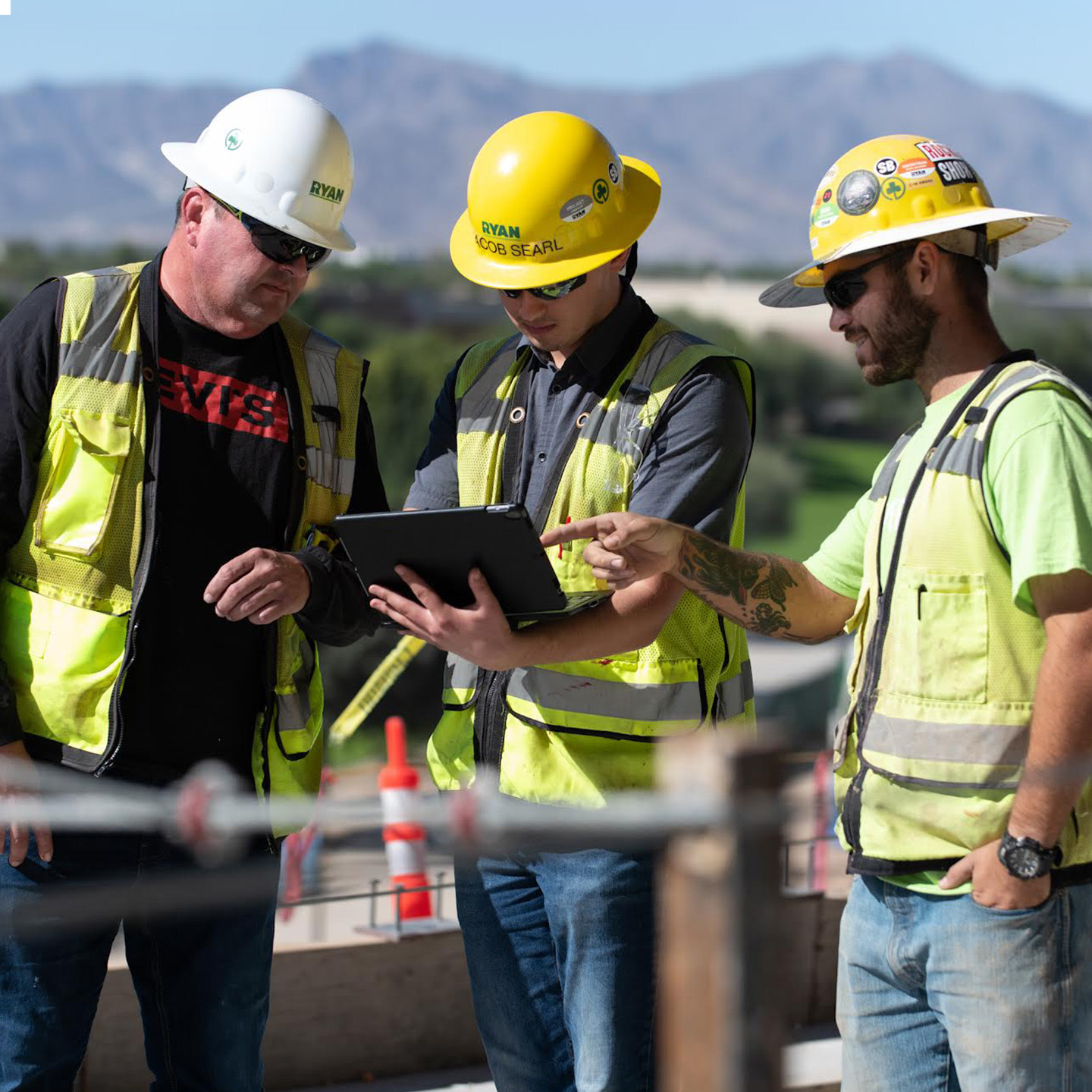 A group of men wearing yellow hard hats and vests