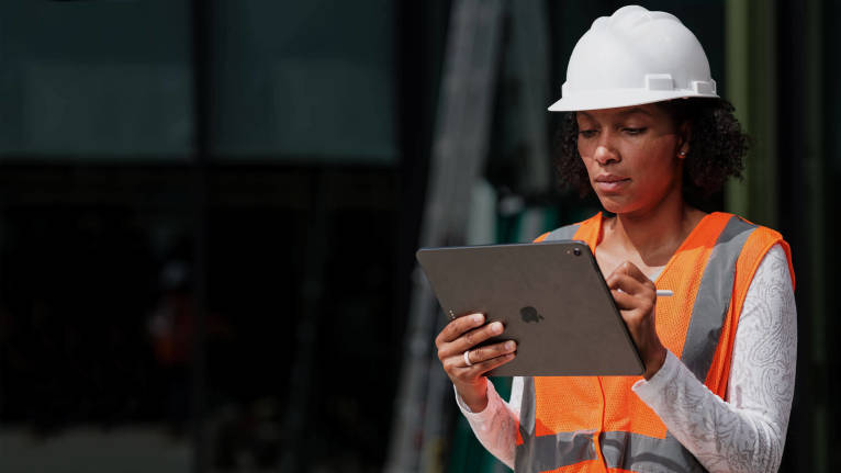 Bauarbeiter, der auf der Baustelle ein Mobilgerät in den Händen hält