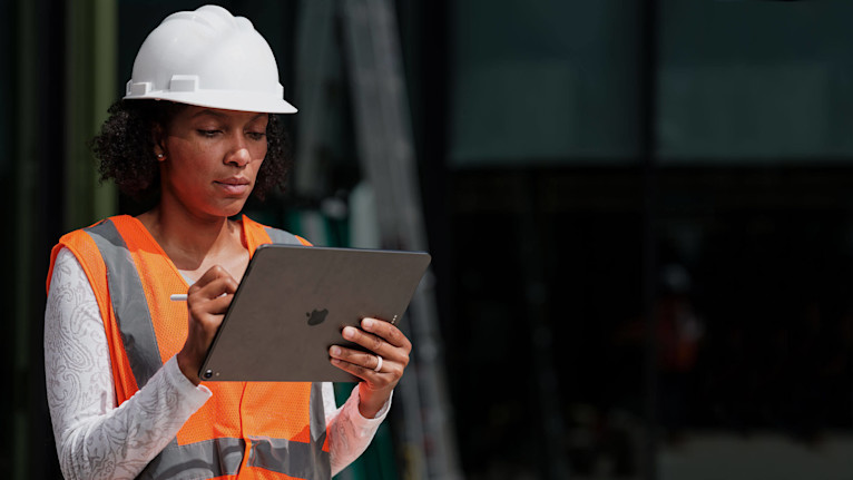 Bauarbeiter, der auf der Baustelle ein Mobilgerät in den Händen hält