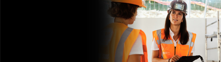 Two women wearing safety equipment having a conversation