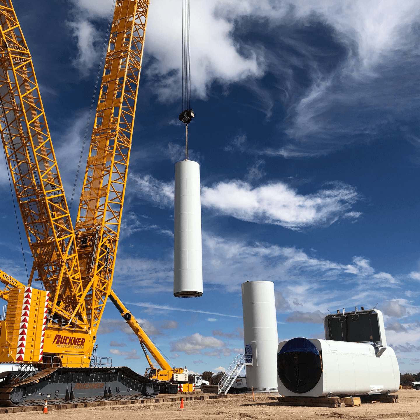 a construction site with a crane and a large white cylinder