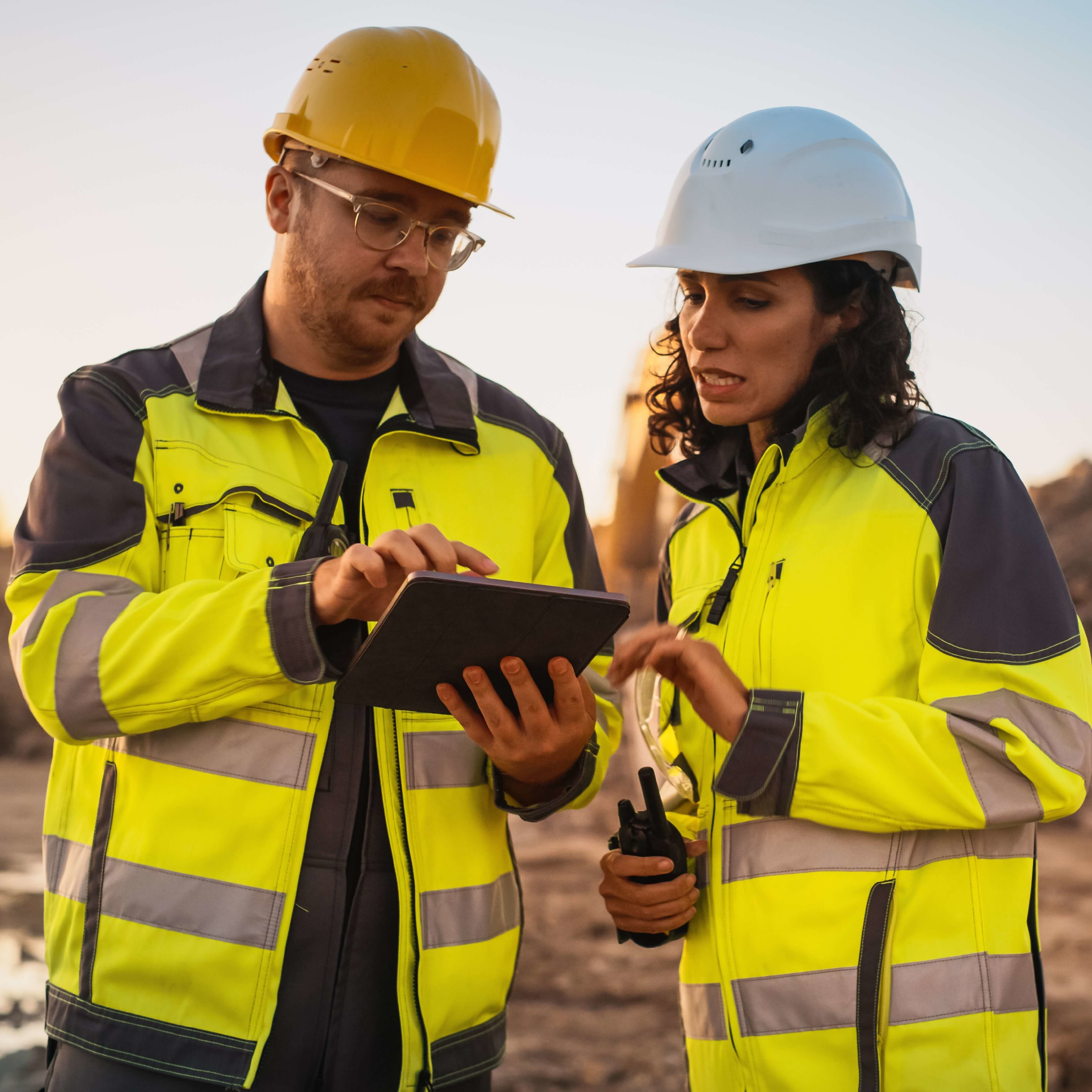 A female and male construction workers using a tablet on site