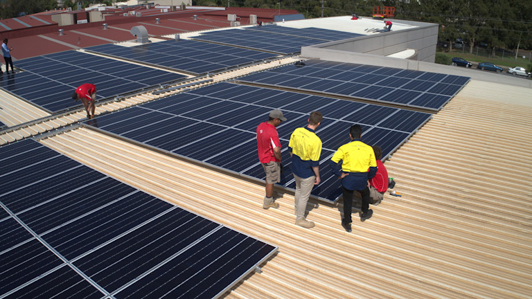 Image of construction workers on a roof inspecting solar panels