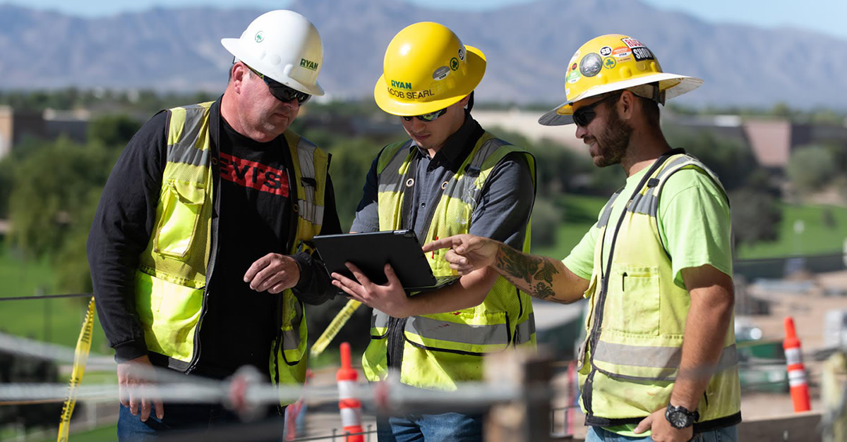 A group of men wearing yellow hard hats and vests