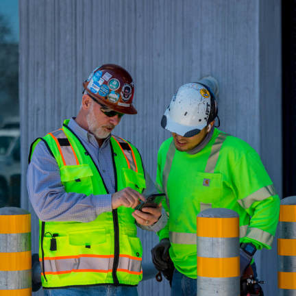 Specialty contractors checking data on Procore on a phone