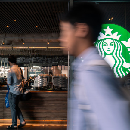 A man walking in front of a starbucks logo