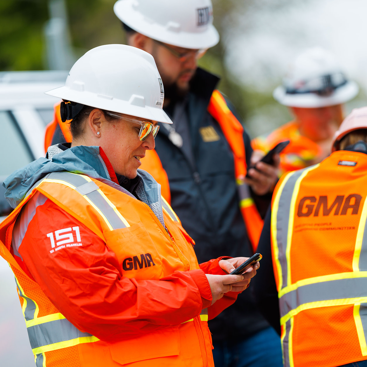 A woman using a phone and wearing safety gear
