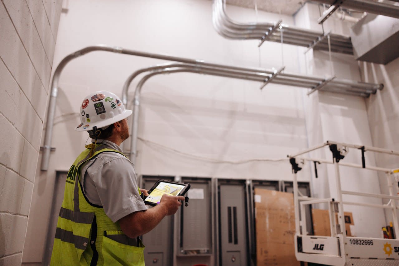 A construction worker looking up at conduit racks