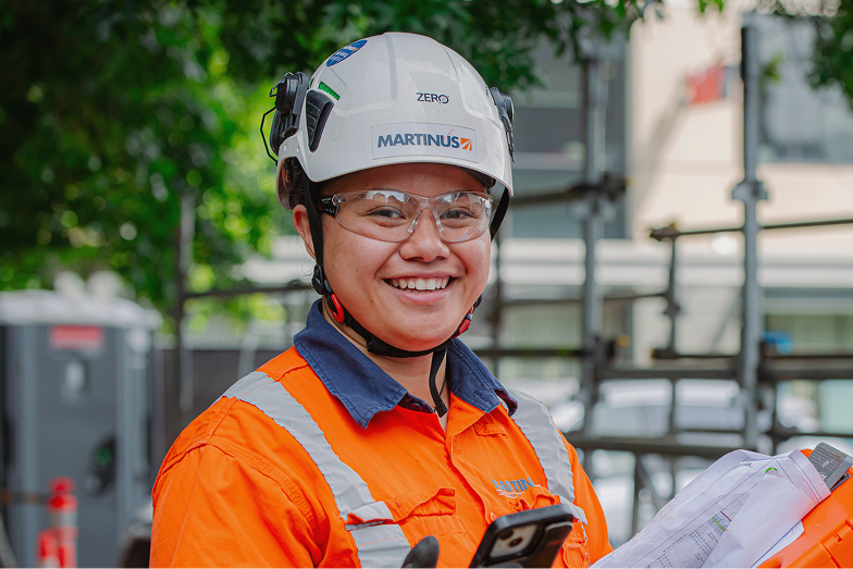 Smiling construction worker in safety gear and helmet at building site.