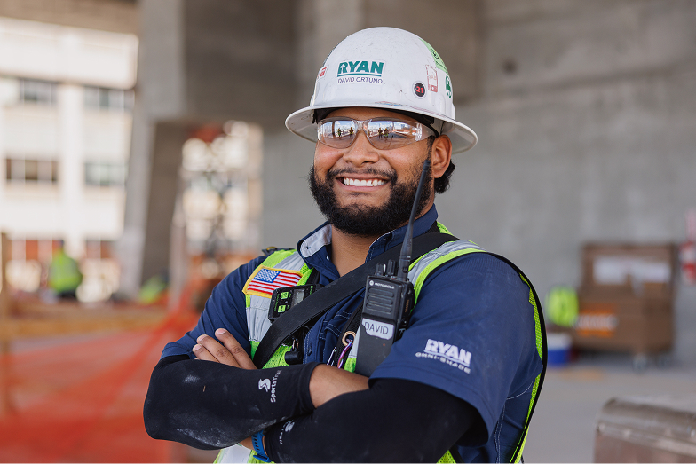 Smiling construction worker in safety gear and helmet at building site.
