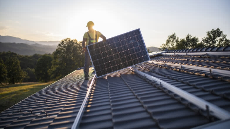 Contractor setting up a solar panel on a roof