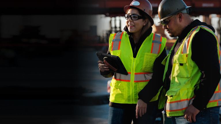 Two construction workers standing side by side with tablets