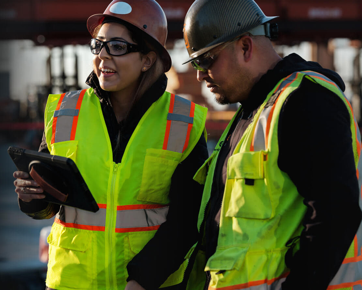 Two construction workers standing side by side with tablets