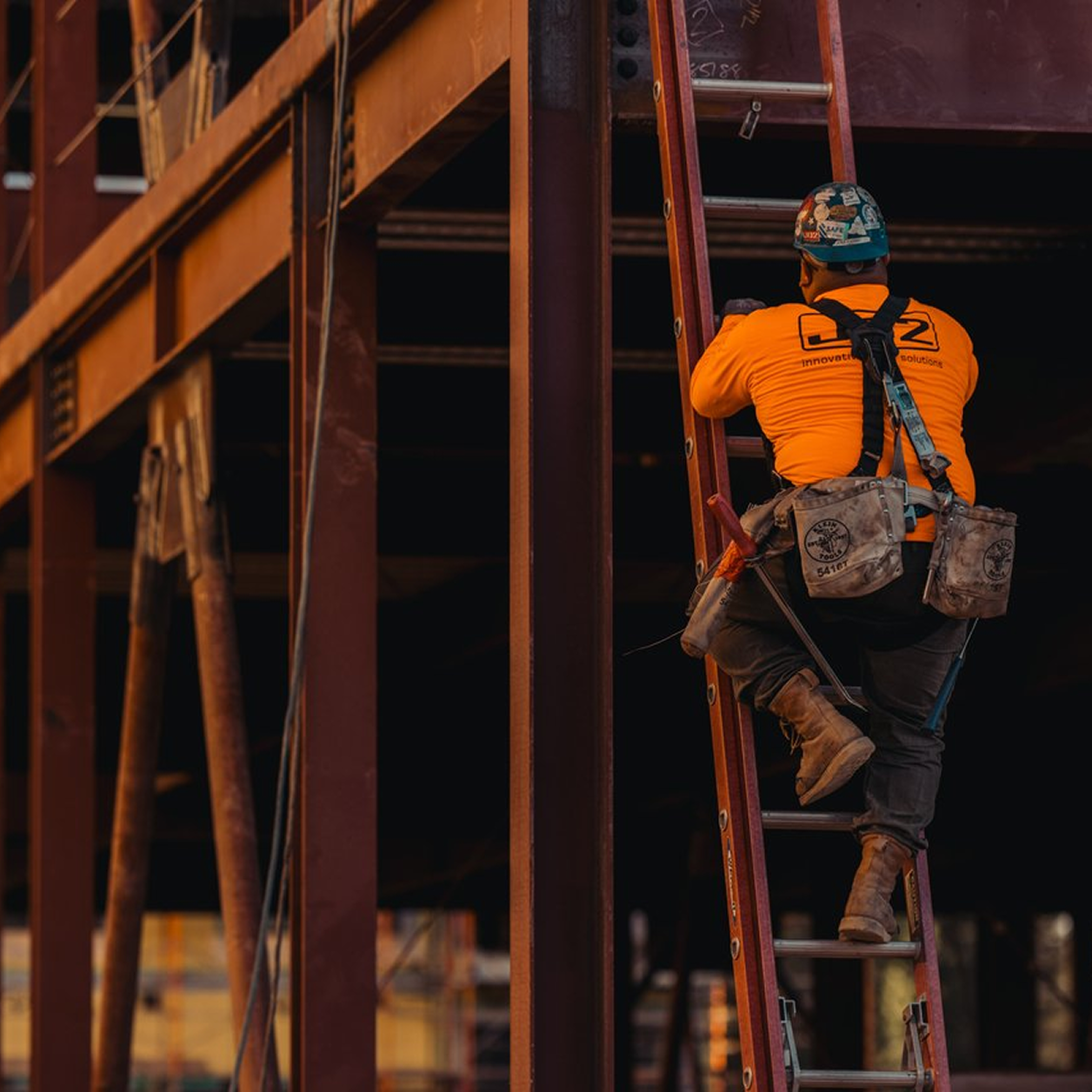 A construction worker climbing up a ladder
