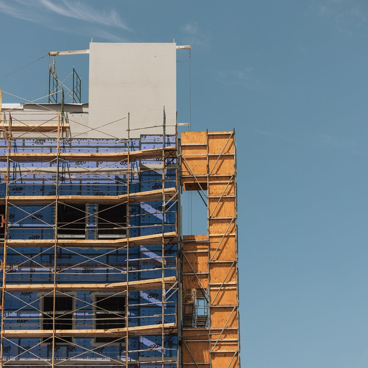 Building under construction with scaffolding against a clear blue sky