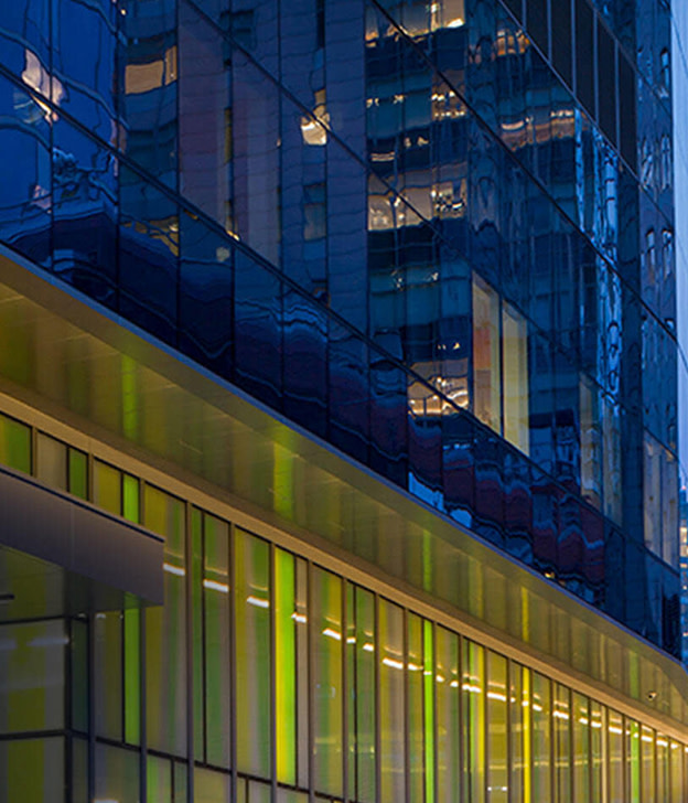 Modern building facade at dusk with illuminated green storefront and lit windows above