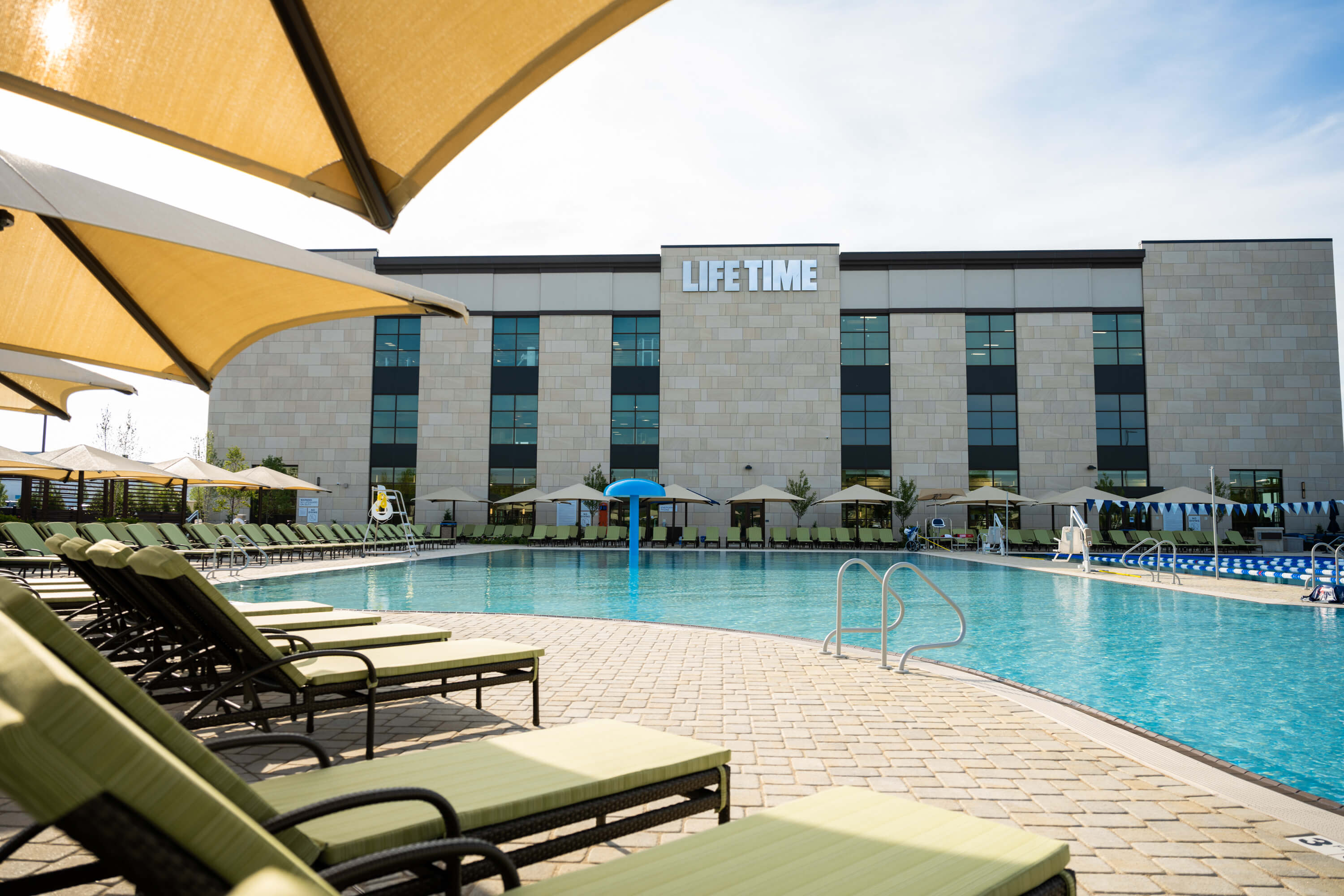 A serene hotel pool area featuring lounge chairs and umbrellas