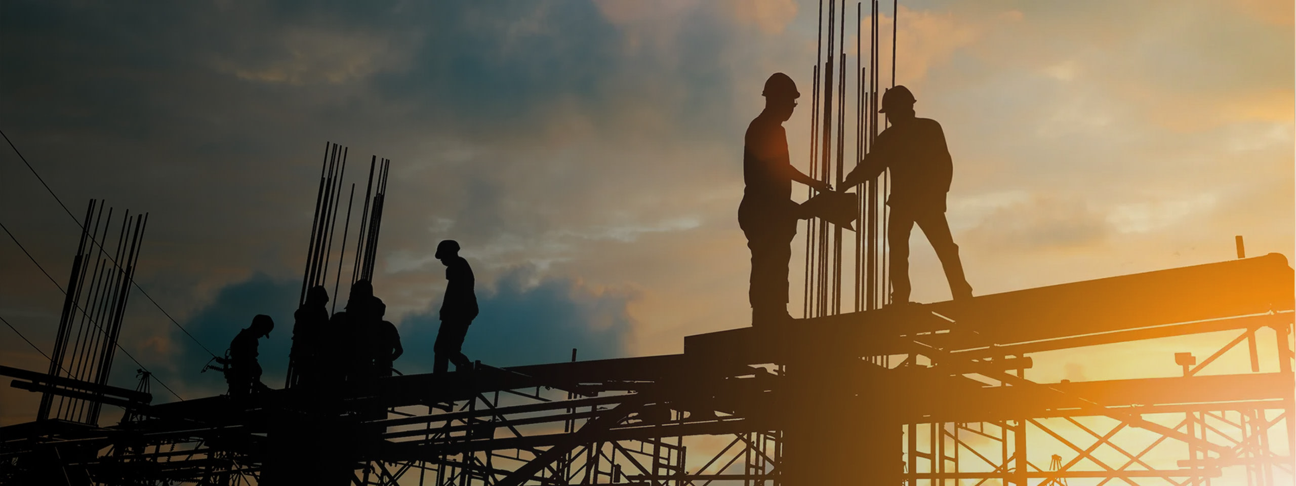 Construction workers on job site at sunset