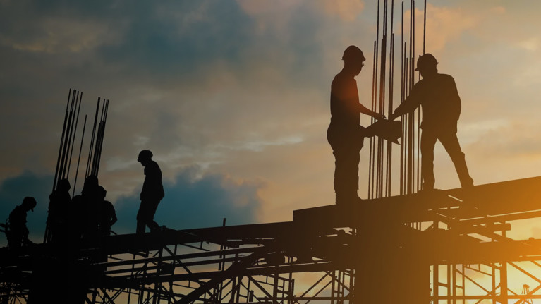 Construction workers on job site at sunset