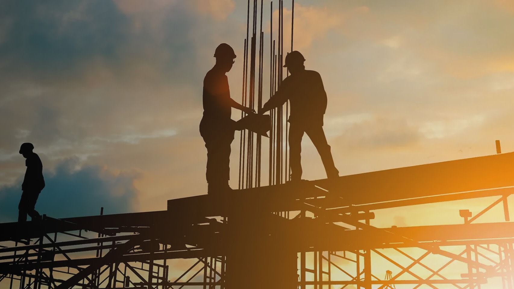 Construction workers on job site at sunset