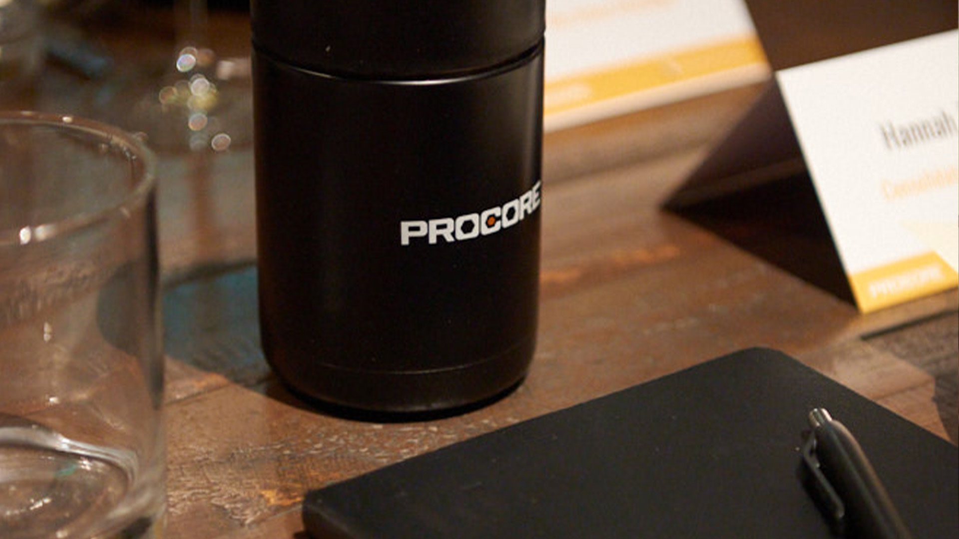 A notebook and a Procore water bottle on a table