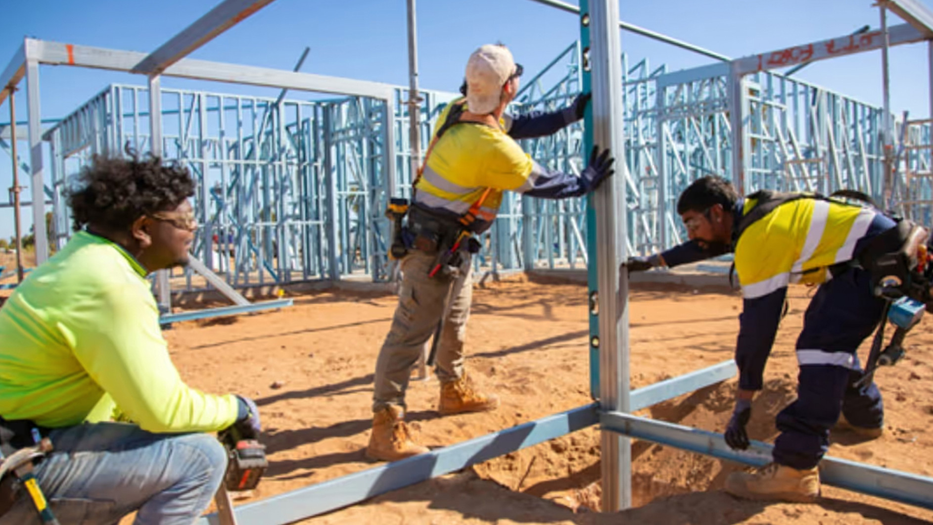 Three Yurra workers collaborating on a frame of a building