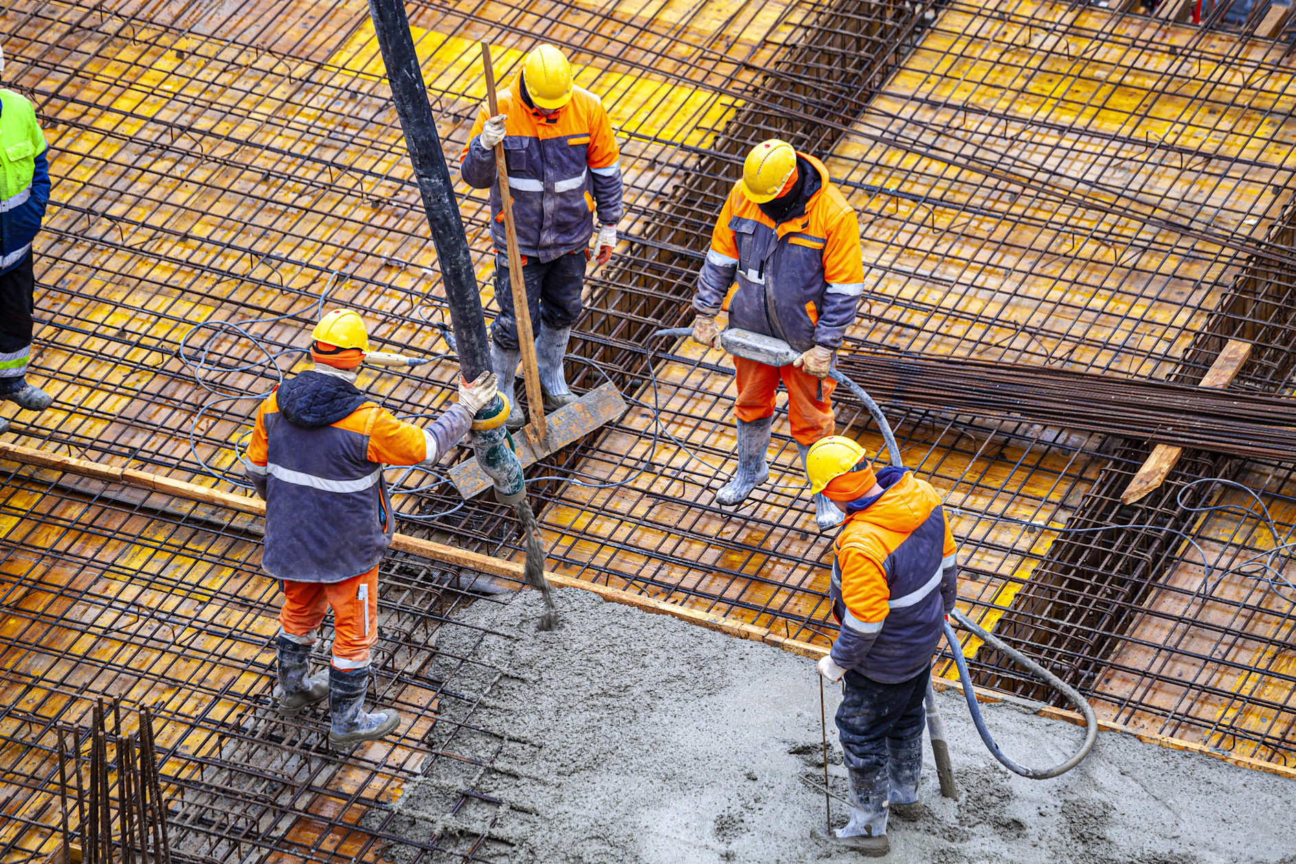 Aerial view of four construction workers pouring cement