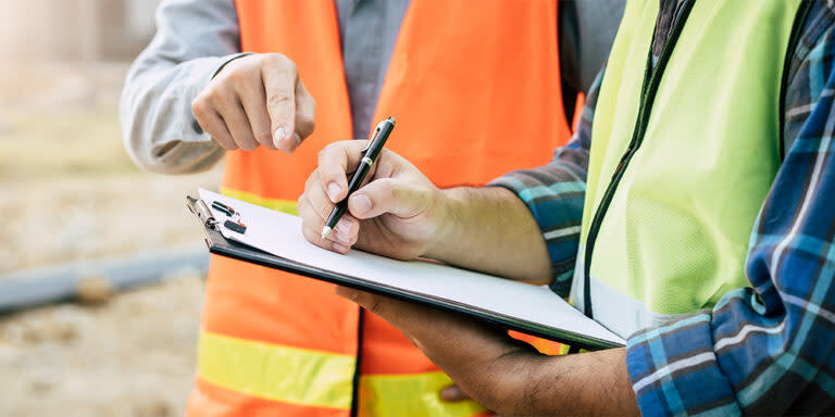 Two construction workers looking at a clipboard