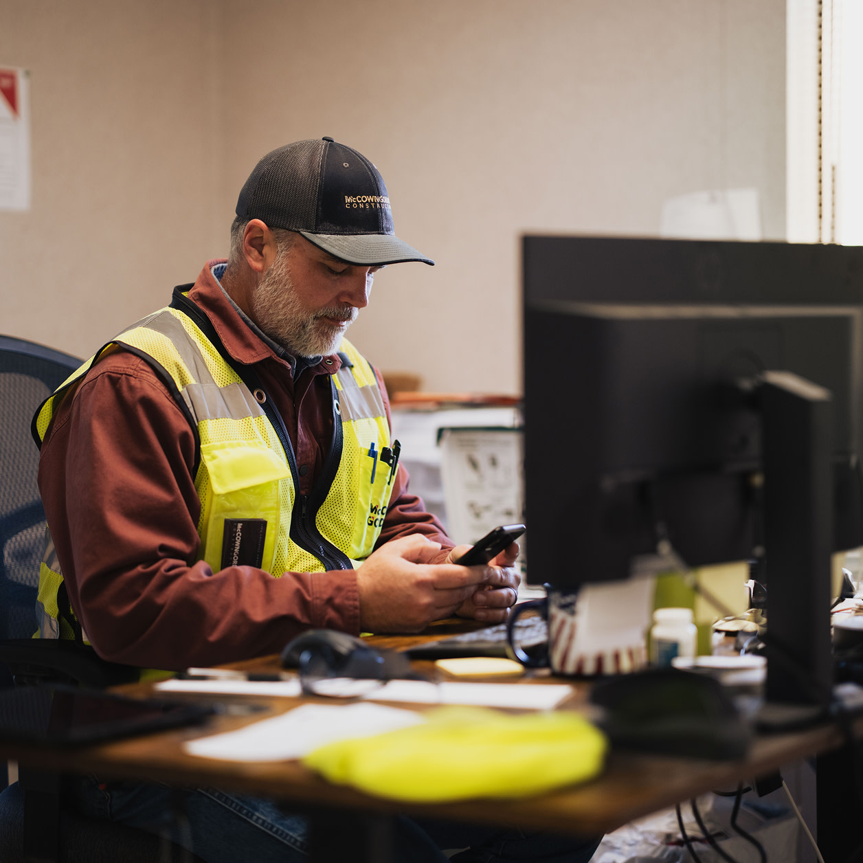 A contractor sitting at an office, while using a phone