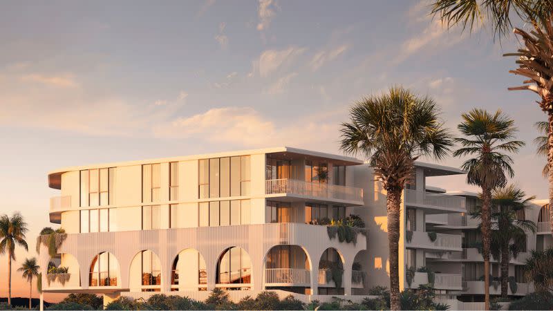 A render of a white, four-storey apartment complex at sunset with palm trees.