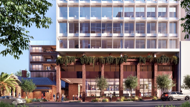 the lower part of a new office building next to an historic home on a sunny day.