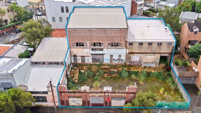 grass grows between a 1938 grocery store in Balmain and the roller garage doors on the site.