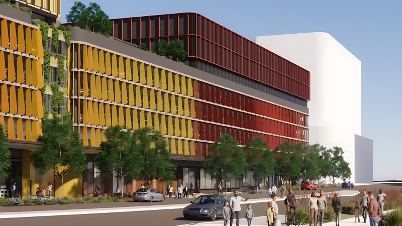 a seven storey carpark with red and yellow on the facade next to a bigger similarly coloured development